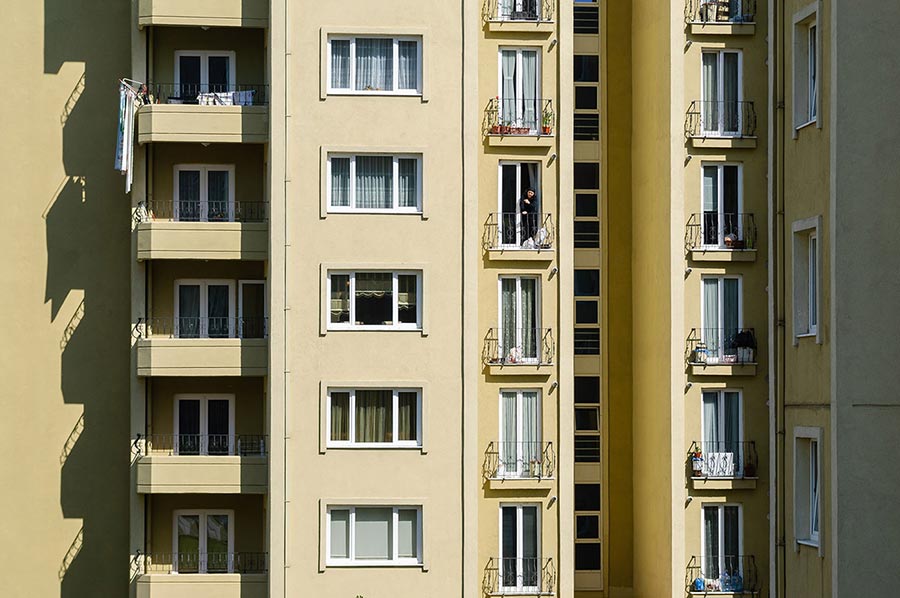 Alte Frau am Fenster eines Hochhauses